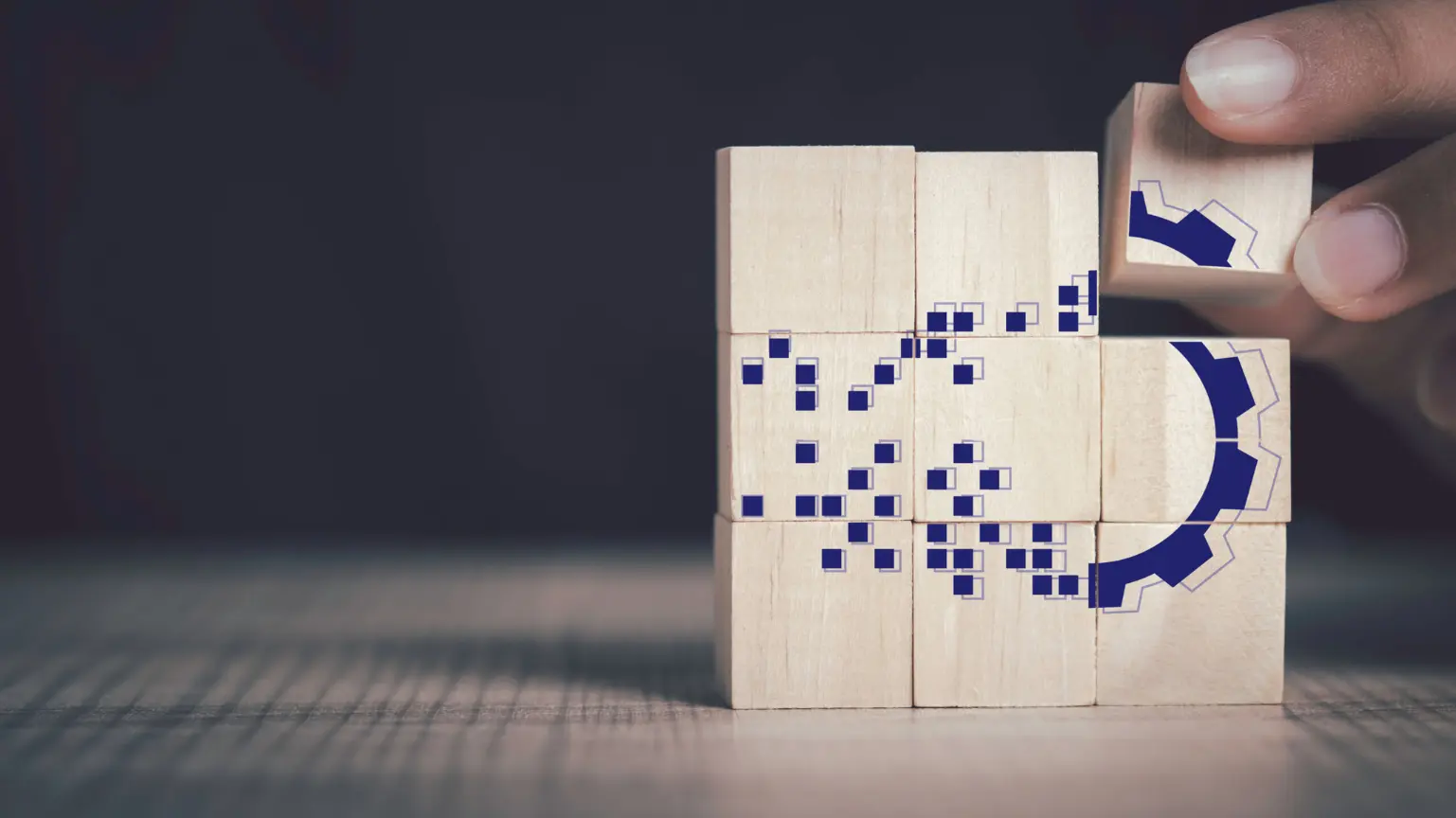 Hand arranging wooden blocks with digital patterns and gear graphics.