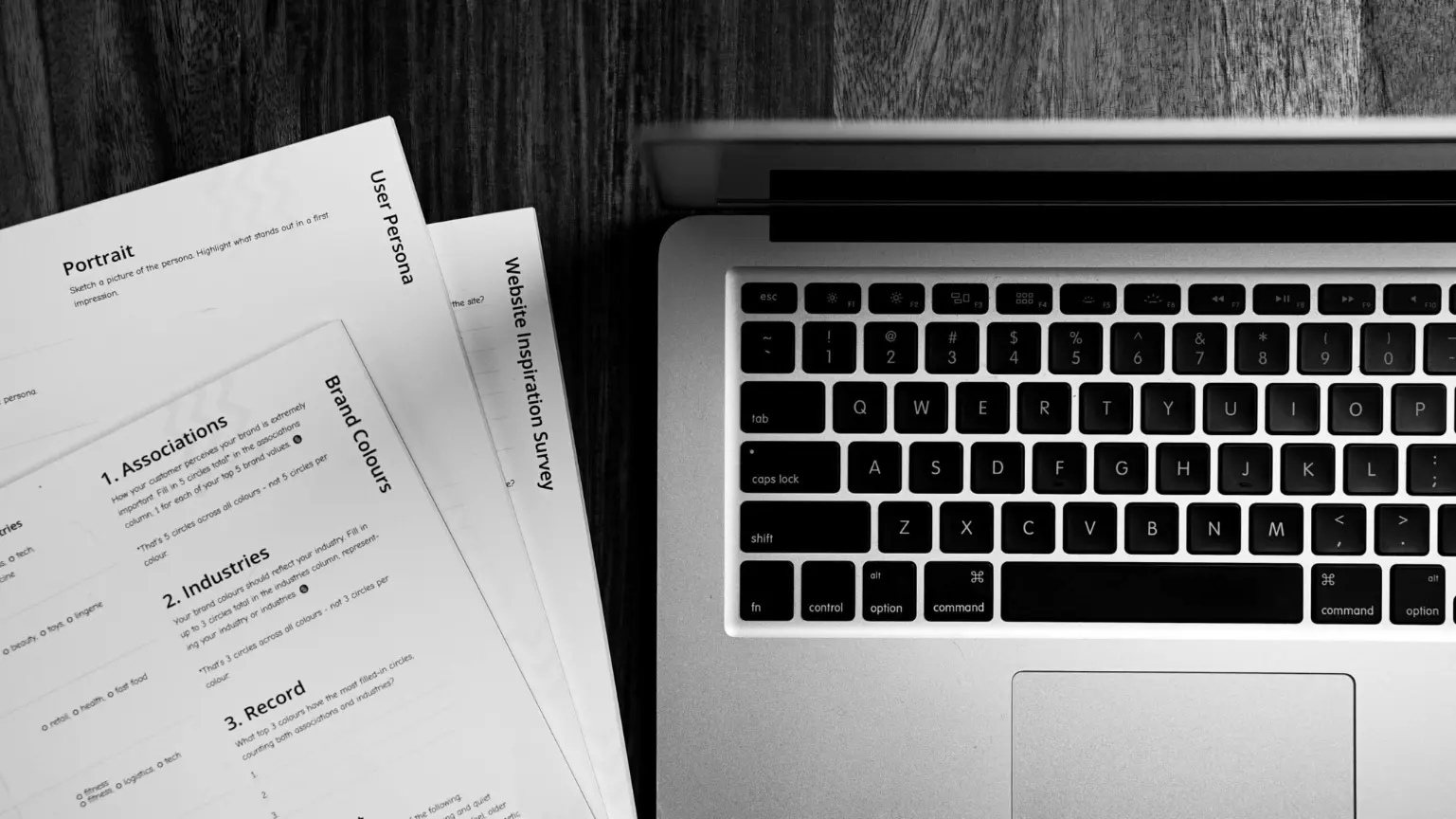 Top-down view of a laptop next to documents labeled user persona and brand guidelines.