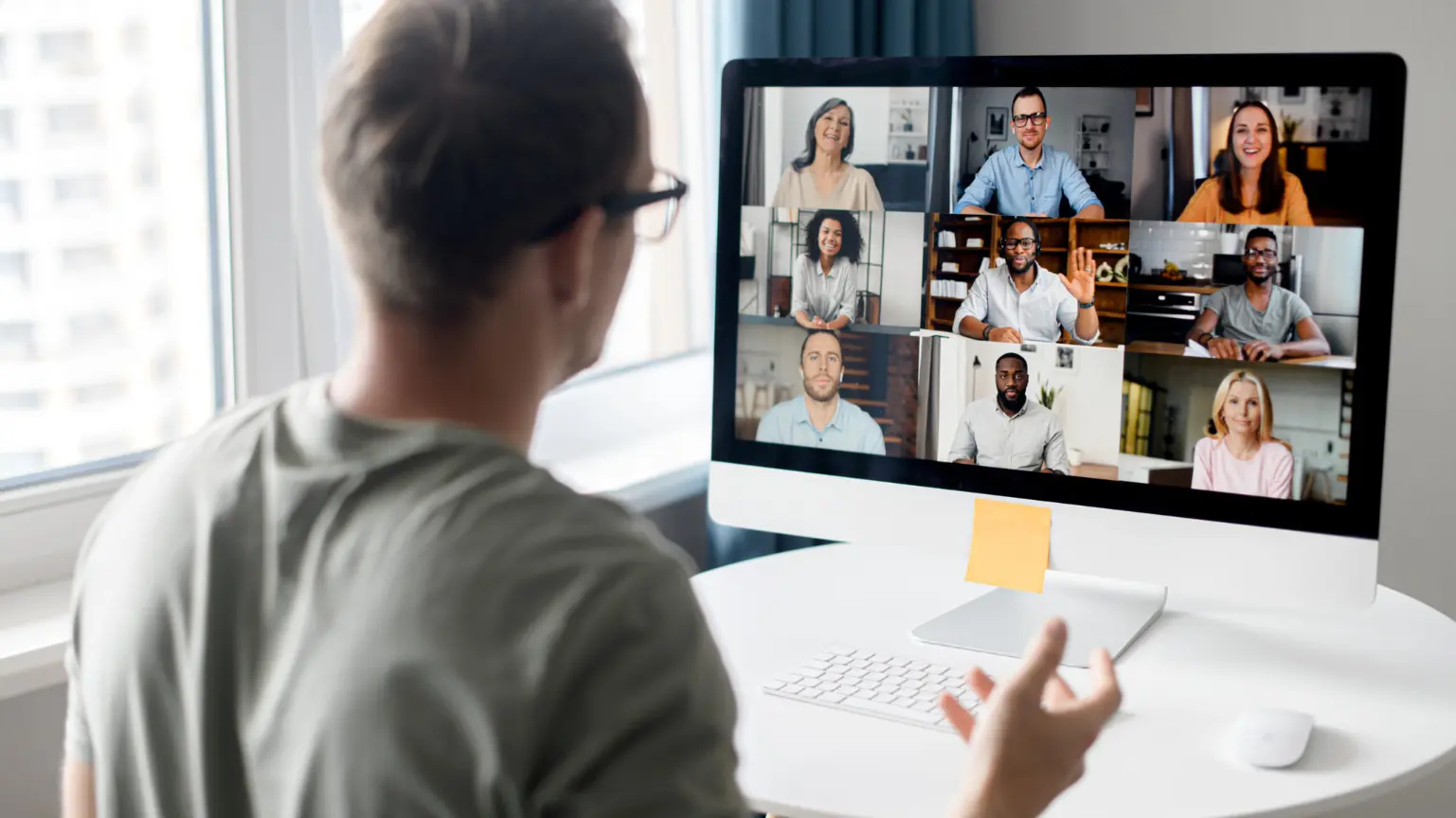 Office team participating in a video conference with colleagues shown on a large screen.