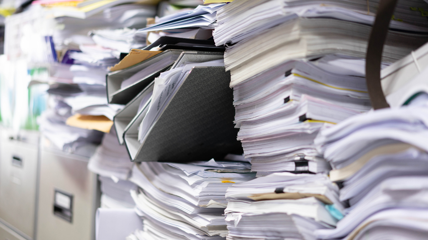 Messy piles of paper documents illustrating the need for business process documentation software to keep company knowledge organized and accessible.